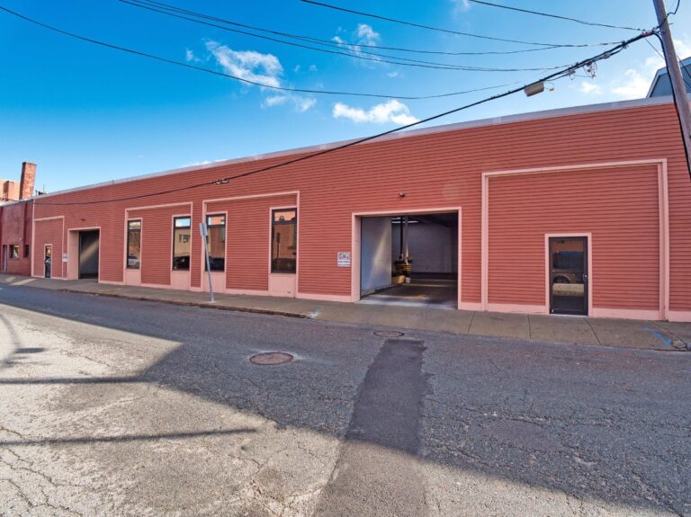 Single-story building with large windows and open garage doors, located on a quiet street.