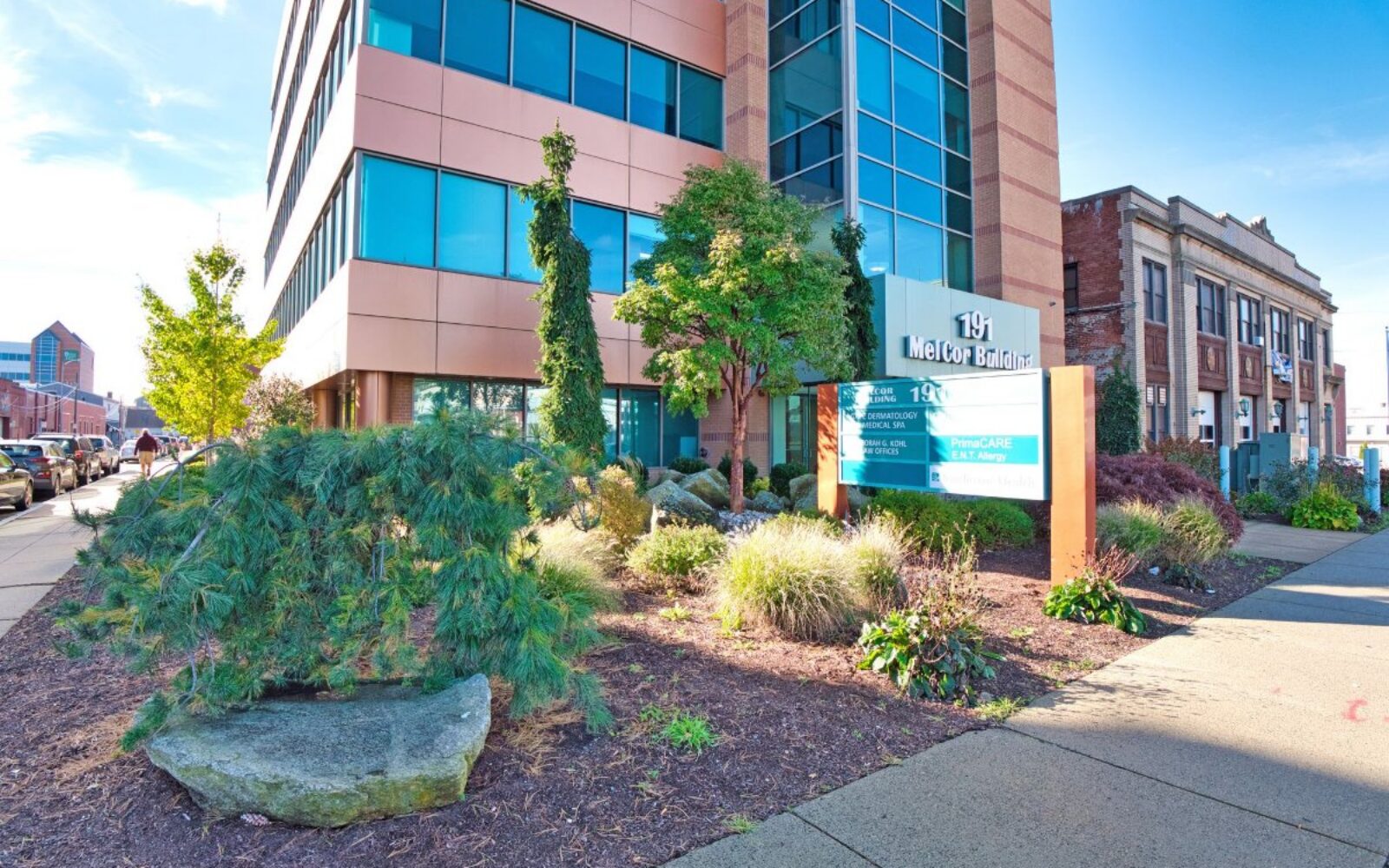 Modern building exterior with landscaping, featuring a sign for "191 MetCor Building" and nearby sidewalk.