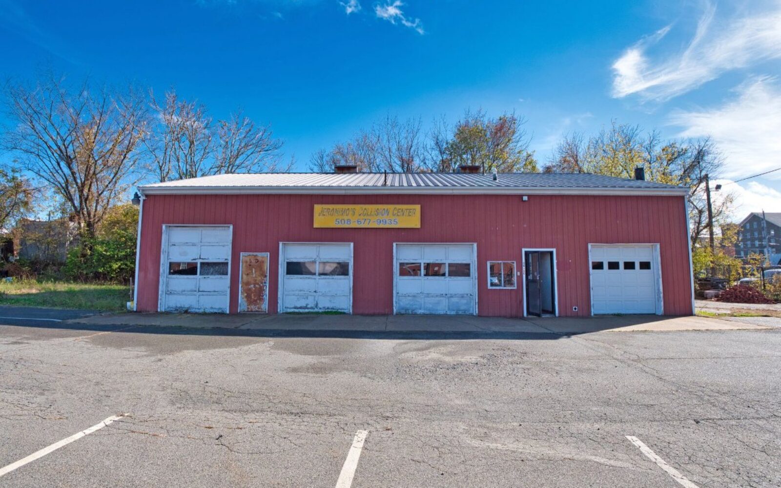 Red building with a yellow sign reading "Jeremiah's Balloon Center," two garage doors, and a clear blue sky.